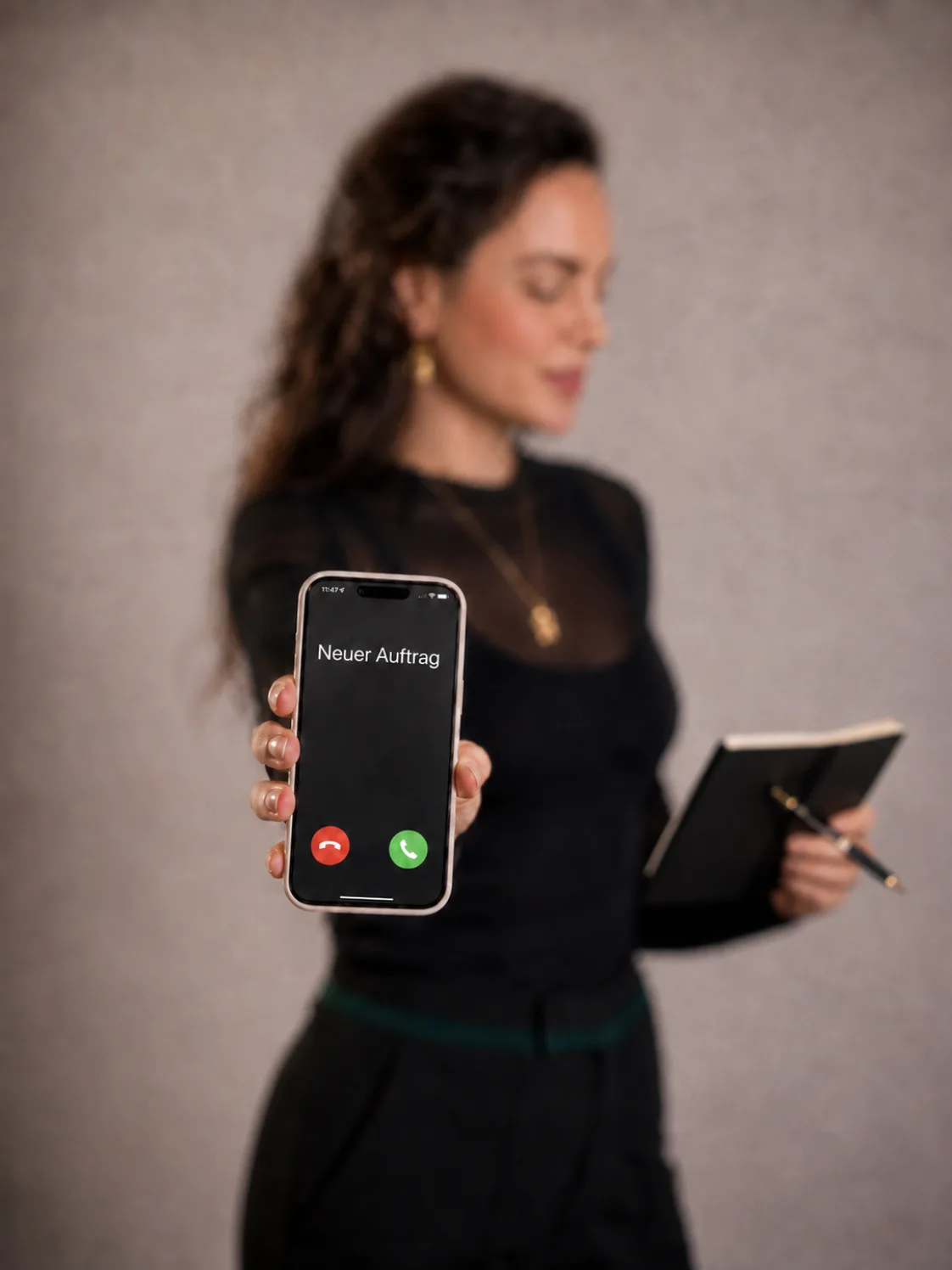 Roxane Freytag hält ein Smartphone, auf dem Display steht Neuer Auftrag